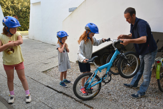 Bart aide ses enfants à sortir leurs vélos.